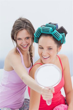 Girls sitting in bed looking in mirror with one girl wearing hair rollers at sleepover Stock Photo - Budget Royalty-Free & Subscription, Code: 400-07057440