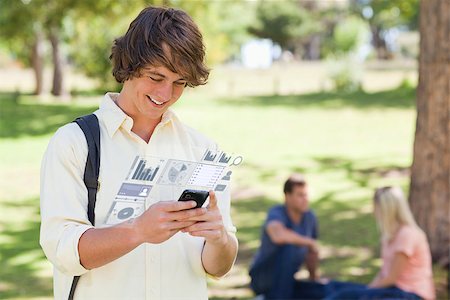 Happy student working on his digital smartphone in bright park Stock Photo - Budget Royalty-Free & Subscription, Code: 400-07057877