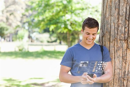 Cheerful handsome student using his digital smartphone in bright park Stock Photo - Budget Royalty-Free & Subscription, Code: 400-07057881