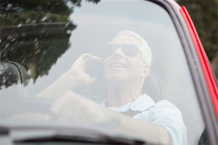 simsearch:400-07057982,k - Smiling handsome man in red convertible having phone call while driving Foto de stock - Super Valor sin royalties y Suscripción, Código: 400-07057976