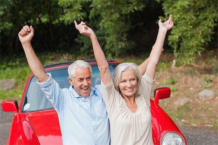 simsearch:400-07057982,k - Cheerful mature couple posing by their red convertible on bright day Foto de stock - Super Valor sin royalties y Suscripción, Código: 400-07058006