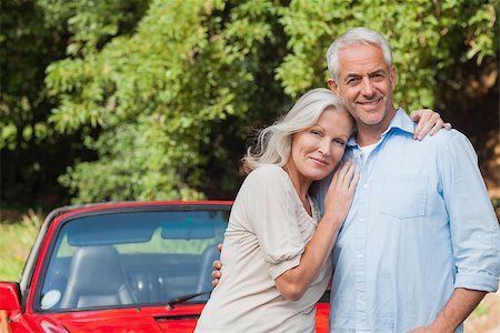 simsearch:400-07057982,k - Cheerful mature couple posing against their red cabriolet Foto de stock - Super Valor sin royalties y Suscripción, Código: 400-07058014