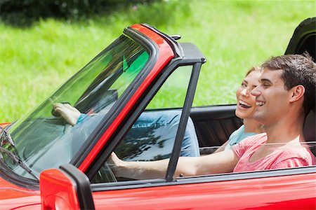 simsearch:400-07058112,k - Smiling young couple having a ride in red cabriolet on a sunny day Photographie de stock - Aubaine LD & Abonnement, Code: 400-07058107