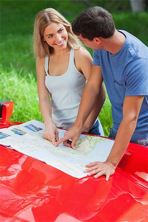 simsearch:400-07058116,k - Smiling young couple reading map on their cabriolet bonnet on a sunny day Stock Photo - Budget Royalty-Free & Subscription, Code: 400-07058161