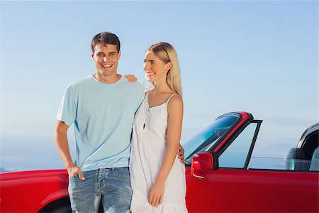 simsearch:400-07058112,k - Smiling cute couple hugging while leaning against their cabriolet Photographie de stock - Aubaine LD & Abonnement, Code: 400-07058188