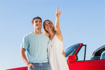 Smiling woman on blue sky background showing something to her handsome boyfriend Stock Photo - Budget Royalty-Free & Subscription, Code: 400-07058194