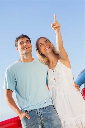 Happy woman on blue sky background showing something to her handsome boyfriend Stock Photo - Budget Royalty-Free & Subscription, Code: 400-07058193