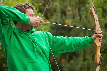 range shooting - Man in green jumper about to shoot arrow at the archery range Stock Photo - Budget Royalty-Free & Subscription, Code: 400-07058549