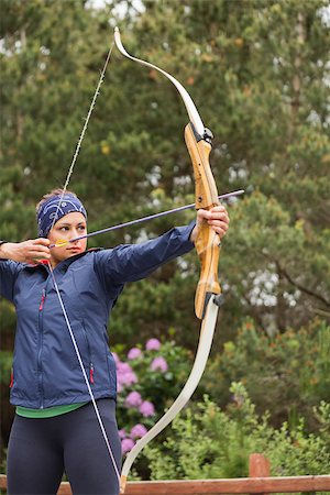 Focused brunette practicing archery in the countryside Foto de stock - Super Valor sin royalties y Suscripción, Código: 400-07058551