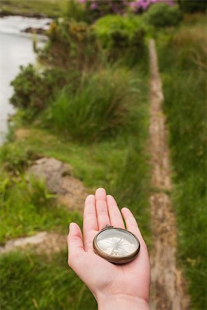 Hand holding old fashioned compass showing the way on a country trail Stockbilder - Microstock & Abonnement, Bildnummer: 400-07058656