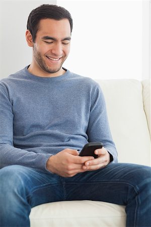 Handsome casual man text messaging in cosy bright living room Stock Photo - Budget Royalty-Free & Subscription, Code: 400-07058726