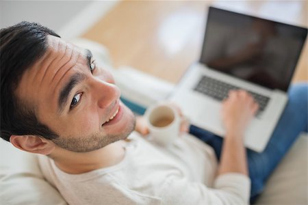 simsearch:6109-08581996,k - High angle view of smiling young man using his laptop in bright living room Fotografie stock - Microstock e Abbonamento, Codice: 400-07058756