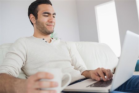 simsearch:6109-08581996,k - Peaceful handsome man having coffee while using his laptop in bright living room Fotografie stock - Microstock e Abbonamento, Codice: 400-07058759