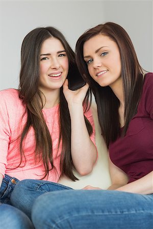 simsearch:400-07059986,k - Two pretty teenage girls calling someone with a mobile phone in a living room Stock Photo - Budget Royalty-Free & Subscription, Code: 400-07058979