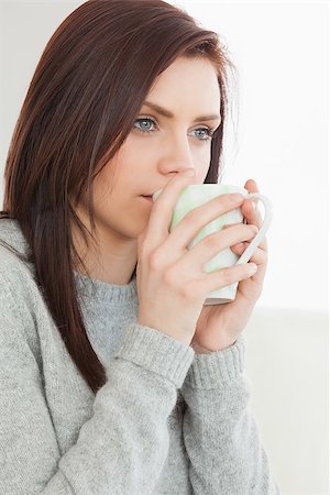 simsearch:6109-08390353,k - Thinking brunette drinking a cup of coffee at home Stock Photo - Budget Royalty-Free & Subscription, Code: 400-07059044