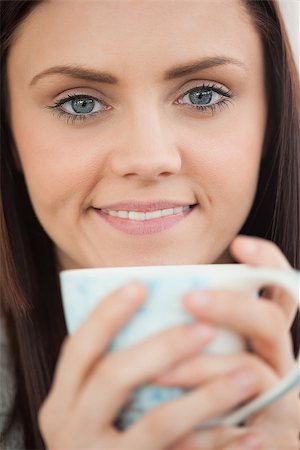 simsearch:400-06932687,k - Smiling brunette holding a cup of coffee and looking at camera Stock Photo - Budget Royalty-Free & Subscription, Code: 400-07059056