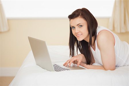 simsearch:400-06932687,k - Happy brunette using a laptop lying on her bed in a bedroom Stock Photo - Budget Royalty-Free & Subscription, Code: 400-07059076