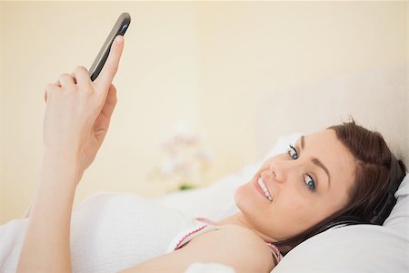 simsearch:400-06932687,k - Happy girl listening music on her smartphone lying on a bed in a bedroom Stock Photo - Budget Royalty-Free & Subscription, Code: 400-07059101