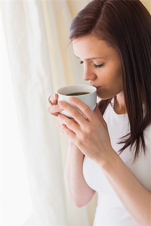 simsearch:400-06932687,k - Thoughtful brunette holding a cup of coffee eyes closed in a bedroom Stock Photo - Budget Royalty-Free & Subscription, Code: 400-07059114