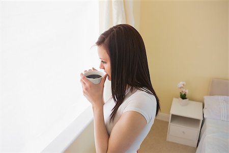simsearch:400-06932687,k - Thoughtful brunette drinking a cup of coffee in a bedroom Stock Photo - Budget Royalty-Free & Subscription, Code: 400-07059110