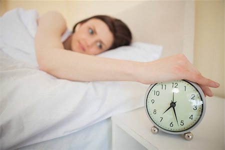 Awakened brunette turning off her alarm clock in her bedroom Photographie de stock - Aubaine LD & Abonnement, Code: 400-07059125