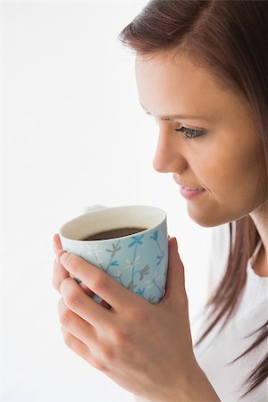 simsearch:400-06932687,k - Thoughtful brunette drinking a cup of coffee on white background Stock Photo - Budget Royalty-Free & Subscription, Code: 400-07059126