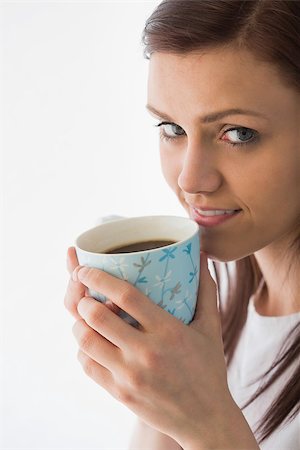 simsearch:400-06932687,k - Thoughtful brunette looking at camera and drinking a cup of coffee on white background Stock Photo - Budget Royalty-Free & Subscription, Code: 400-07059127