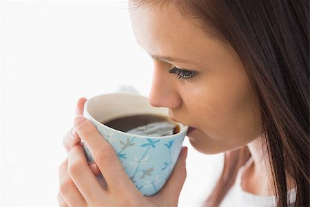 simsearch:400-06932687,k - Calm brunette drinking a cup of coffee on white background Stock Photo - Budget Royalty-Free & Subscription, Code: 400-07059130