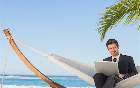 Businessman sitting in hammock using laptop looking at camera on beach Stock Photo - Budget Royalty-Free & Subscription, Code: 400-07059246