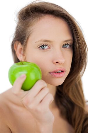 Unsmiling brunette model holding an apple on white background Stock Photo - Budget Royalty-Free & Subscription, Code: 400-07059683