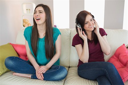 simsearch:400-07059986,k - Girl listening to music with her friend beside her on the sofa at home in living room Stock Photo - Budget Royalty-Free & Subscription, Code: 400-07059993