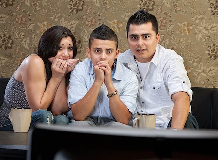 se ronger les ongles - Scared young Latino family watching television together Photographie de stock - Aubaine LD & Abonnement, Code: 400-07050202