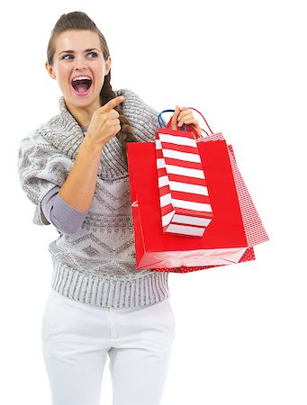simsearch:400-06772308,k - Surprised young woman in sweater with shopping bags pointing on copy space Stockbilder - Microstock & Abonnement, Bildnummer: 400-07050622