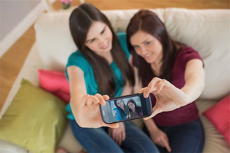 simsearch:400-07059986,k - Two friends on the couch taking a selfie with smartphone at home in the living room Stock Photo - Budget Royalty-Free & Subscription, Code: 400-07060018