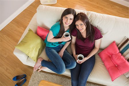 simsearch:400-07059986,k - Two happy friends drinking coffee and looking at camera on the couch at home in the living room Stock Photo - Budget Royalty-Free & Subscription, Code: 400-07060011