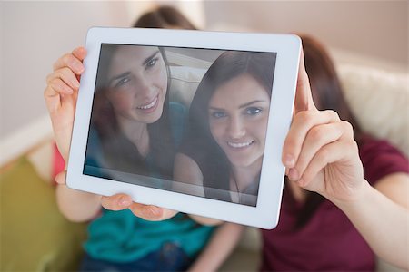 Two happy friends on the couch taking a selfie with tablet pc at home in the living room Stock Photo - Budget Royalty-Free & Subscription, Code: 400-07060020