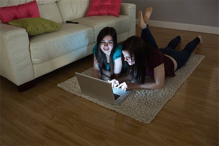 simsearch:400-07059986,k - Two happy friends lying on floor using laptop together in the dark at home in the living room Stock Photo - Budget Royalty-Free & Subscription, Code: 400-07060030