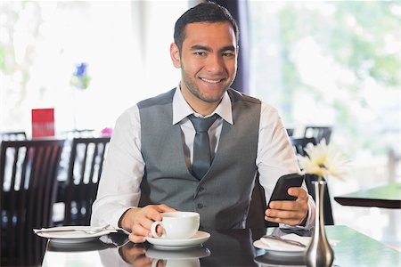 simsearch:400-07137867,k - Businessman in a restaurant holding phone smiling at camera Fotografie stock - Microstock e Abbonamento, Codice: 400-07060745