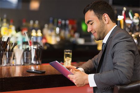 person sitting bar stool - Attractive businessman sitting at bar reading drinks menu Stock Photo - Budget Royalty-Free & Subscription, Code: 400-07060742