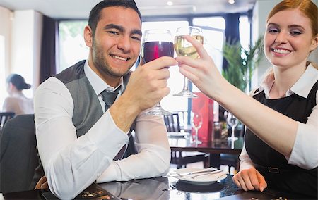 simsearch:400-07137867,k - Smiling business partners clinking wine glasses looking at camera in a restaurant Fotografie stock - Microstock e Abbonamento, Codice: 400-07060775