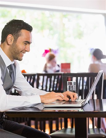 simsearch:400-07137867,k - Smiling businessman looking at laptop screen in a restaurant Fotografie stock - Microstock e Abbonamento, Codice: 400-07060784