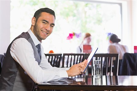 Happy businessman using tablet and smiling at camera in a restaurant Stock Photo - Budget Royalty-Free & Subscription, Code: 400-07060786