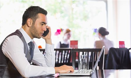 simsearch:400-07137867,k - Serious businessman man calling on phone using laptop in a restaurant Fotografie stock - Microstock e Abbonamento, Codice: 400-07060787