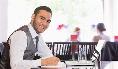 simsearch:400-07137867,k - Smiling businessman writing while looking at camera in a restaurant Fotografie stock - Microstock e Abbonamento, Codice: 400-07060789