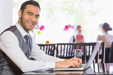 simsearch:400-07137867,k - Smiling businessman working on laptop  and looking at camera Fotografie stock - Microstock e Abbonamento, Codice: 400-07060783