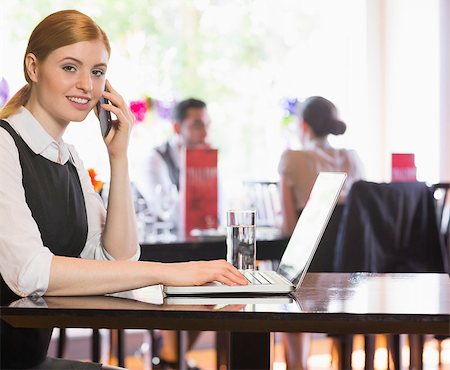 simsearch:400-07137867,k - Smiling businesswoman looking at camera while calling on phone in a restaurant Fotografie stock - Microstock e Abbonamento, Codice: 400-07060796