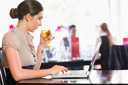 restaurant work teenager - Attractive businesswoman holding wine glass while working on laptop in a restaurant Photographie de stock - Aubaine LD & Abonnement, Code: 400-07060808