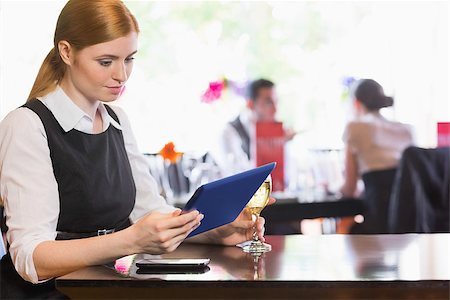 simsearch:400-07137867,k - Businesswoman looking at tablet screen while holding wine glass in a restaurant Fotografie stock - Microstock e Abbonamento, Codice: 400-07060801