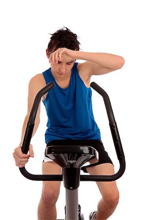Male teenager wiping brow exhausted after fitness workout on an exercise bike.  White background, Stock Photo - Budget Royalty-Free & Subscription, Code: 400-07062429
