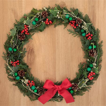 Christmas floral wreath decoration with green baubles, red bow, holly and winter greenery over oak background. Stock Photo - Budget Royalty-Free & Subscription, Code: 400-07086933